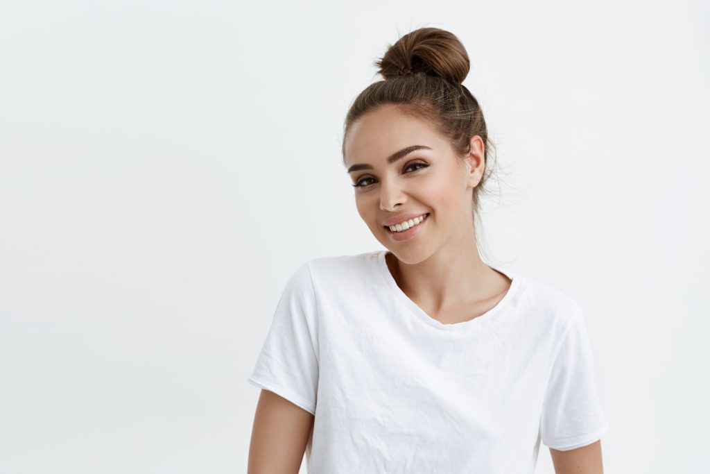 woman in white shirt with hair in bun smiling