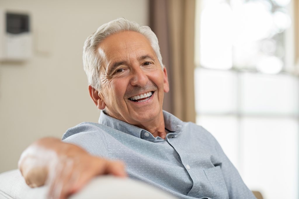 older gentleman sitting on couch smiling