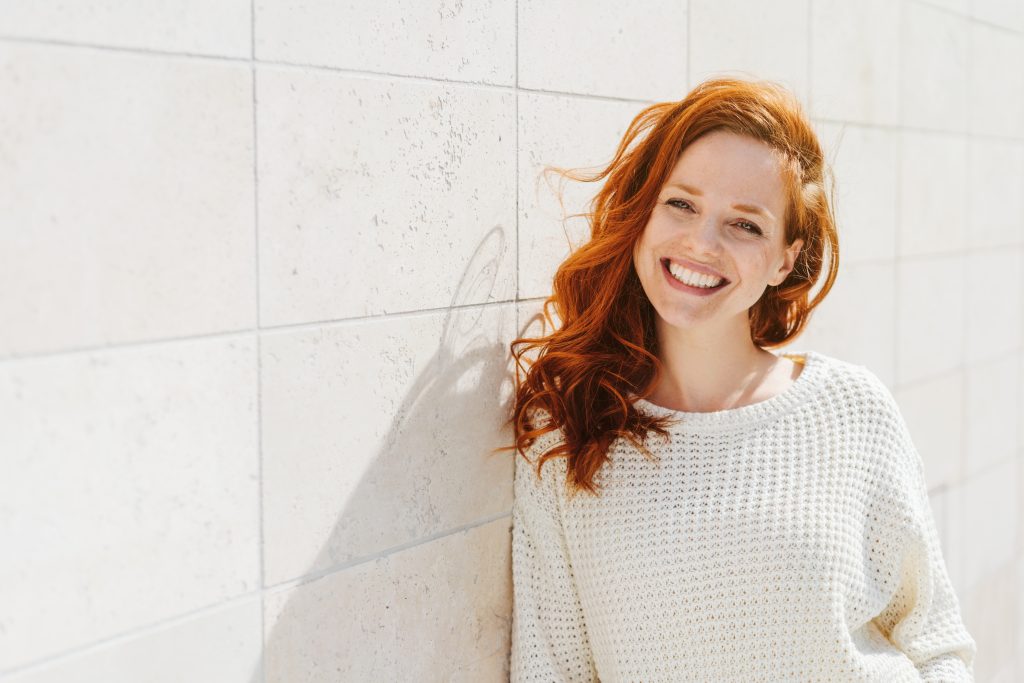 redheaded woman in white sweater smiling