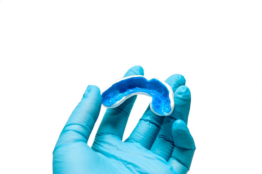 gloved hand holding mouthguard