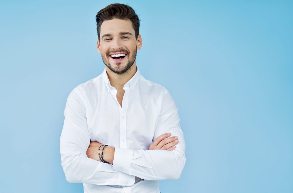 man in white shirt with crossed arms laughing