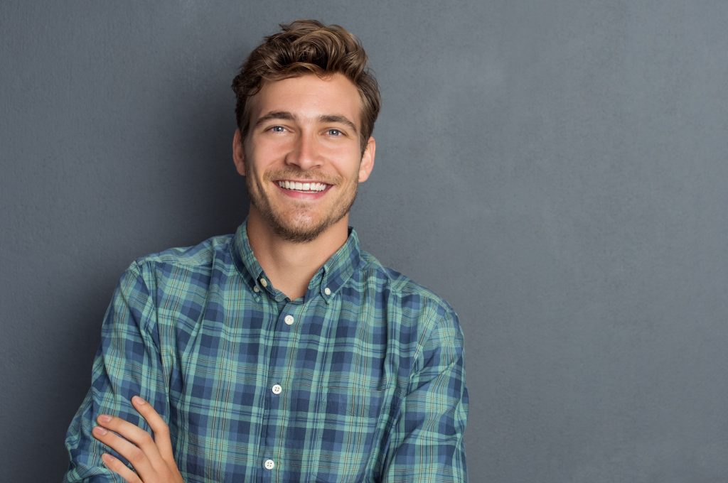 young man in checkered shirt smiling