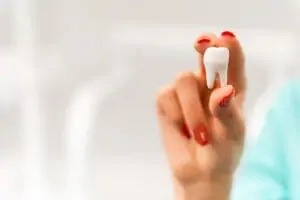 Woman with red nail polish holding a tooth